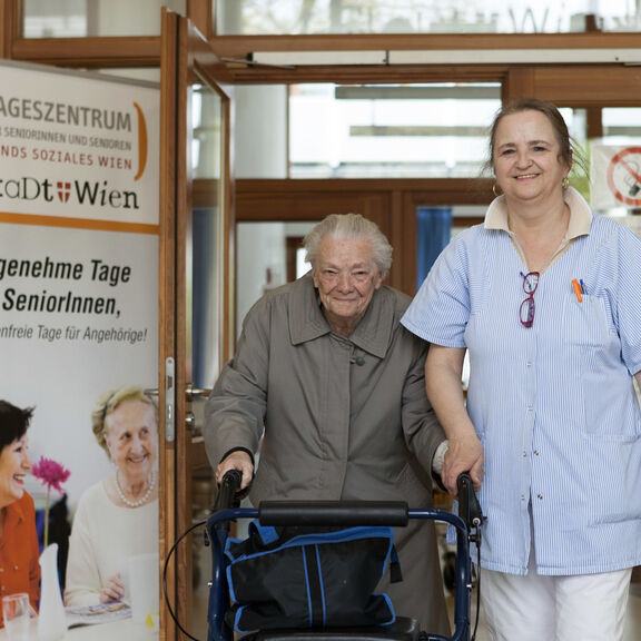 Pflegerin geht gemeinsam mit älterer Person im Tageszentrum Favoriten (Bild: FSW)